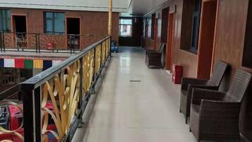 A hotel corridor with wicker chairs, a railing, and a view of the pool area.