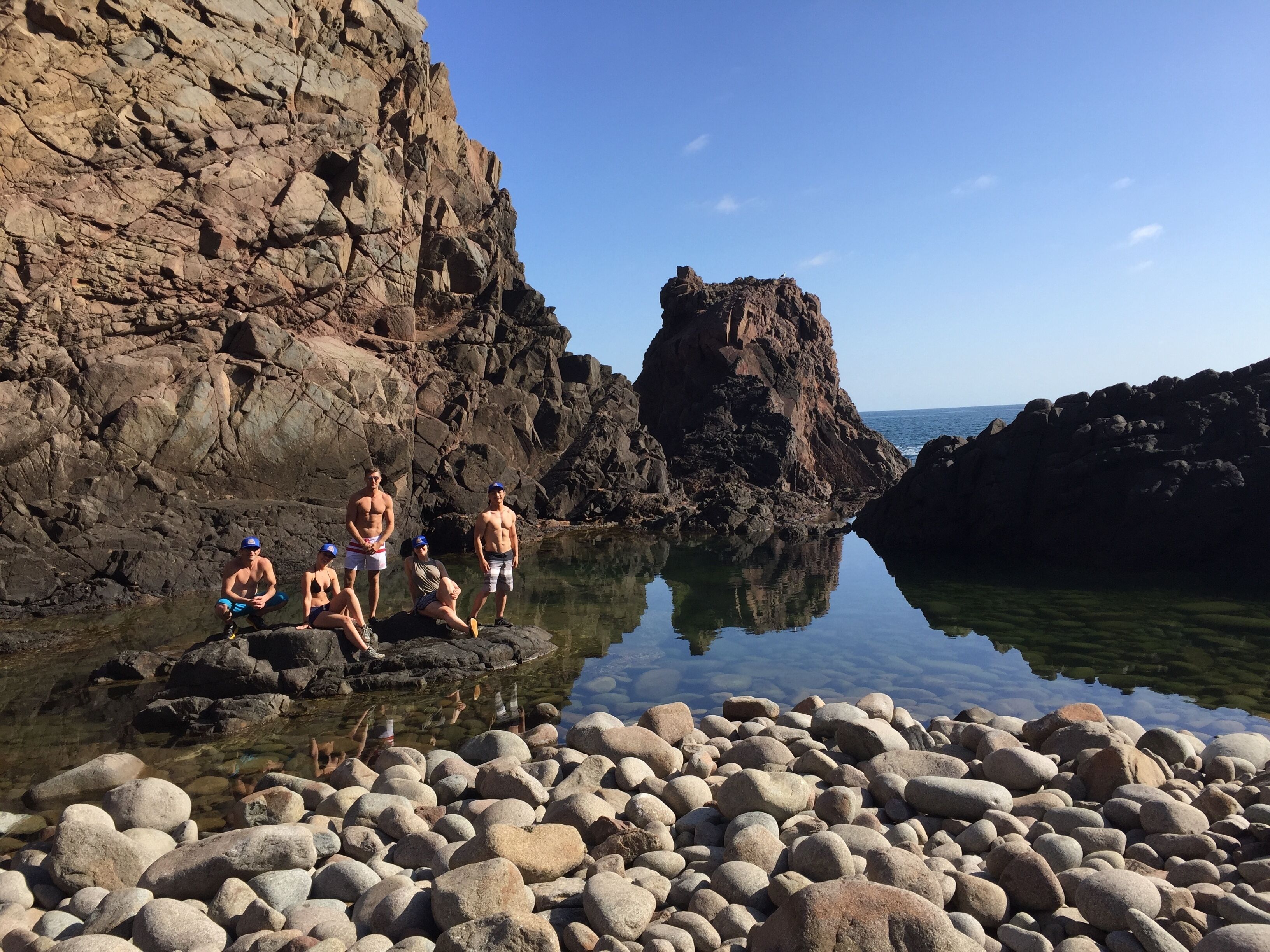 Una costa rocosa con agua cristalina que refleja el cielo y las rocas circundantes.
