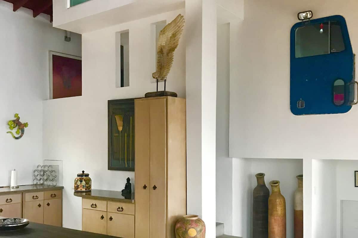 A room with a dining table, a wooden cabinet, a vase, and a blue object on the wall.
