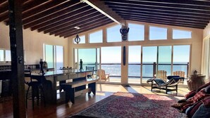 A spacious living area with a large window overlooking the ocean, a wooden floor, and a cozy seating area with a rug. - Baja Off the Grid, Luxury Nature Glamping Retreat (Cabo Punta Banda)