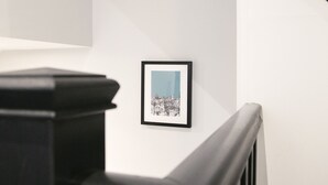 Un escalier avec une main courante noire et un tableau encadré accroché au mur.