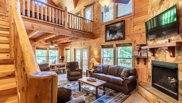 A log cabin interior with a loft bedroom, a fireplace, a television, and a dining area. - Bearfoot's Nantahala Retreat-Pastoral View - Internet - Pool table - Fire Pit (Bryson City)