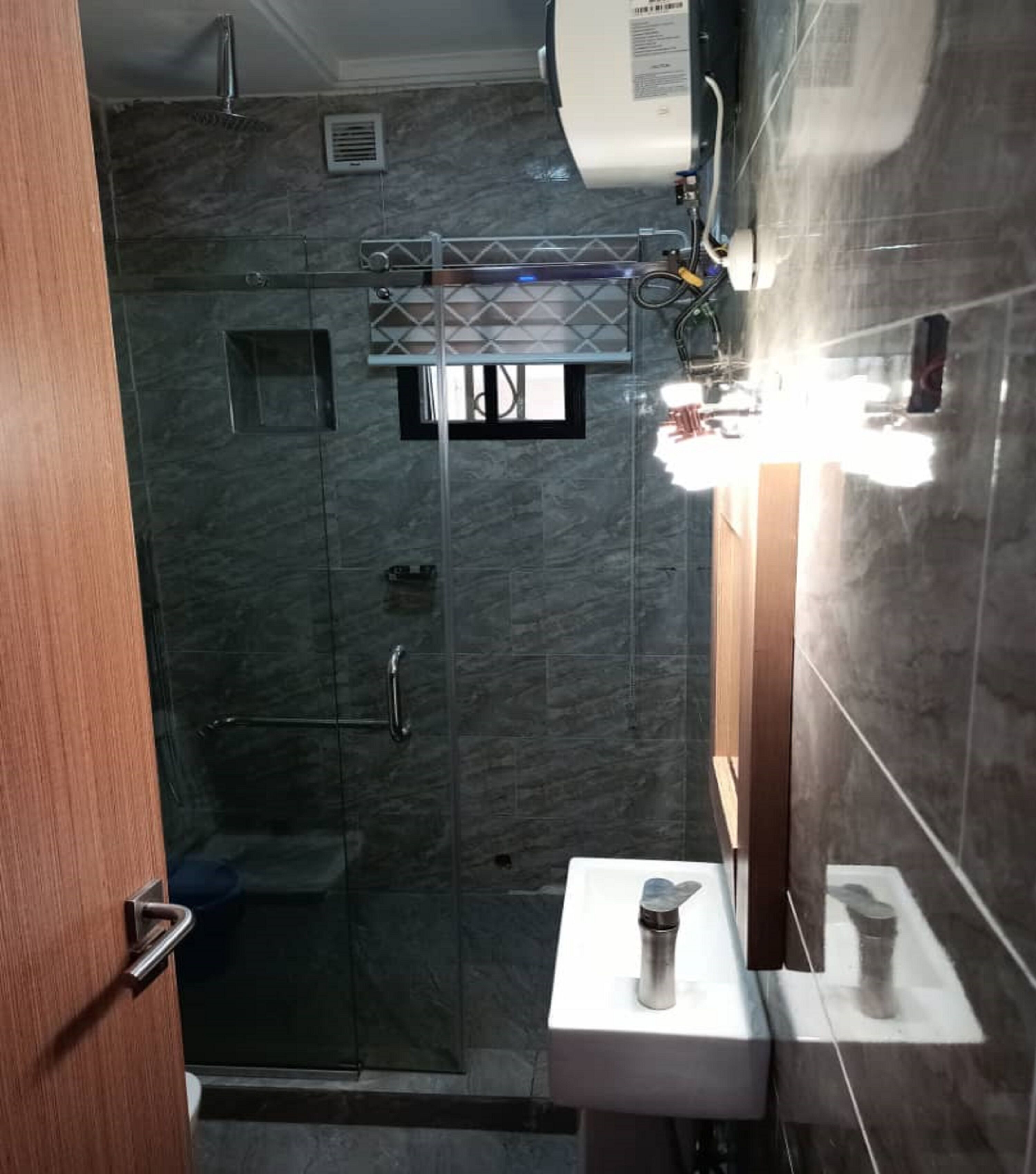 Un baño moderno con cabina de ducha de vidrio, lavamanos empotrado y espejo.