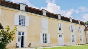 Un bâtiment à deux étages avec des volets blancs et un toit en briques.
