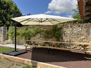Een terras met een stenen muur, een houten bank en een grote parasol.