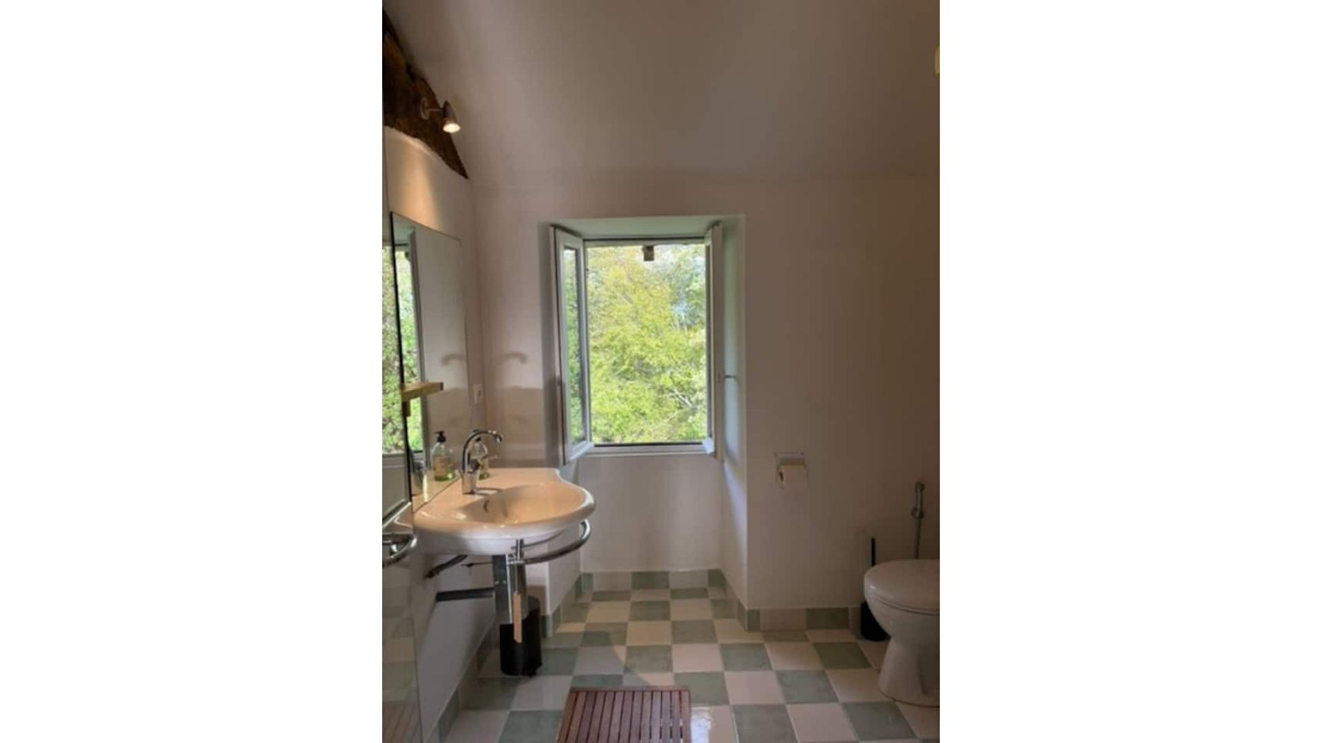 Un baño con lavamanos, espejo y ventana.
