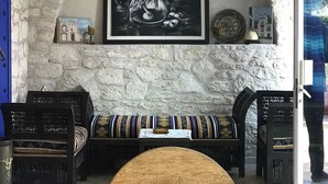 Um interior acolhedor com uma parede de pedra, uma pintura em preto e branco emoldurada, luminárias pendentes de vime e uma mesa de centro de madeira.