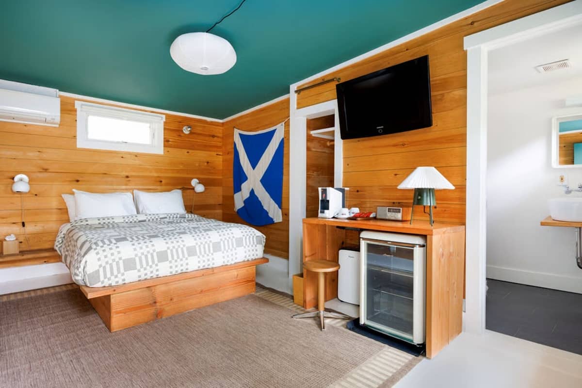 A room with a bed, a desk with a computer, a TV, and a flag.