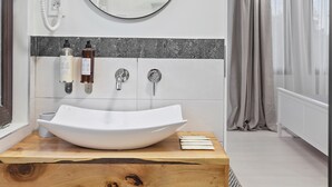 Ein modernes Badezimmer mit freistehendem Waschbecken, einem runden Spiegel und einer Duschvorhang.