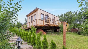 Ein Holzhaus mit Balkon, umgeben von einem Steinweg und kleinen Bäumen.