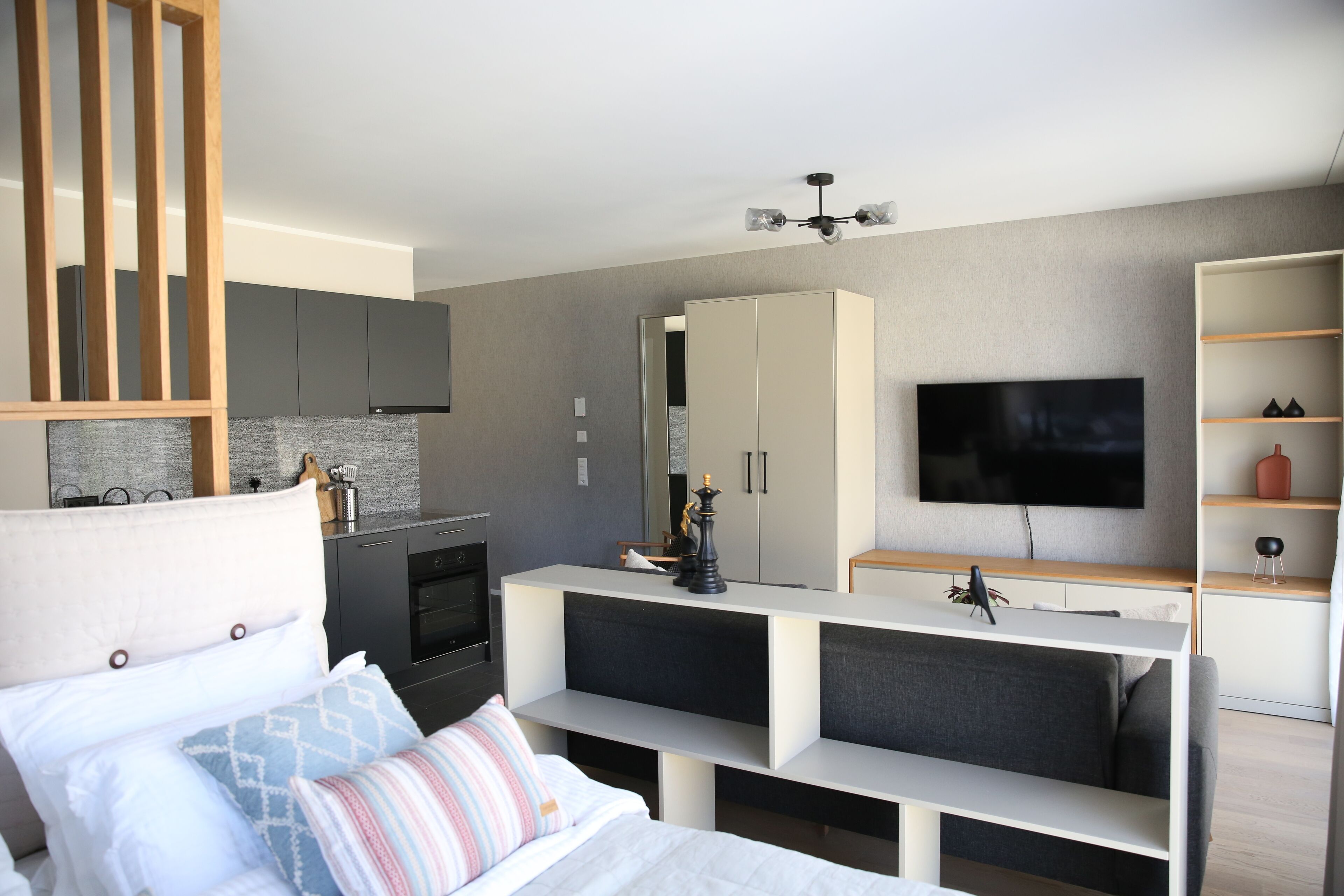 Een moderne hotelkamer met een bed, een televisie, een kitchenette en een zithoek.