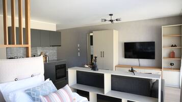 Een moderne hotelkamer met een bed, een televisie, een kitchenette en een zithoek.