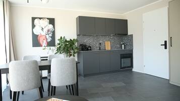 Une cuisine moderne avec des meubles gris, un plan de travail en marbre et un coin repas comprenant une table et des chaises.