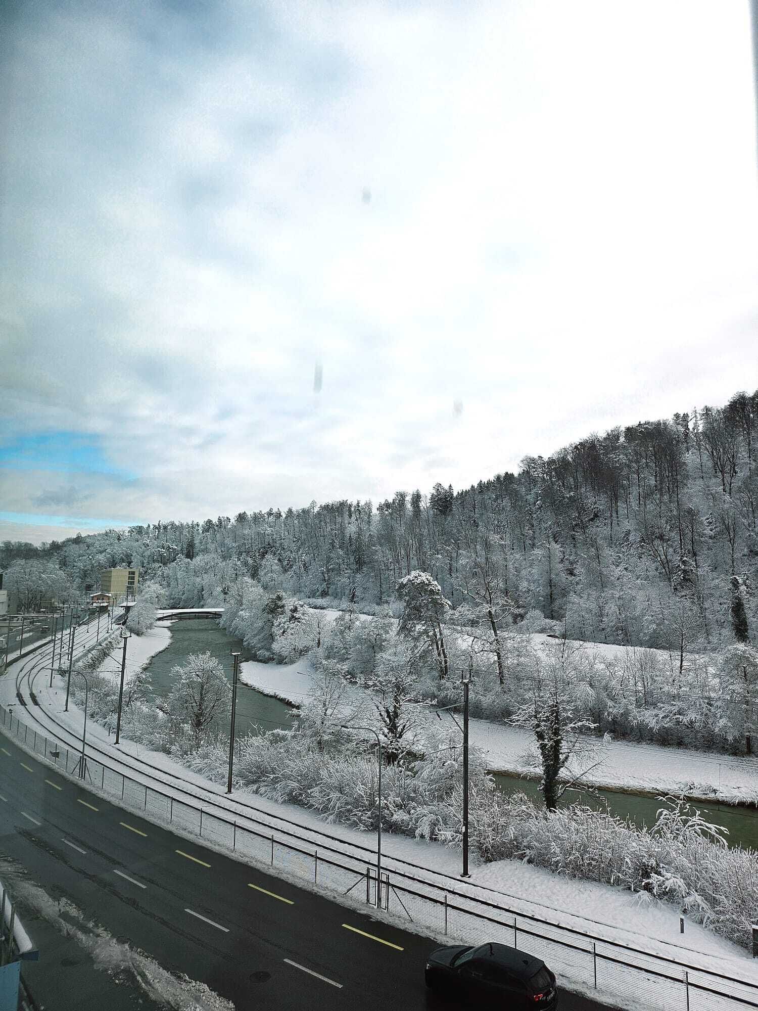 A snow-covered landscape with a river, a bridge, and a road.
