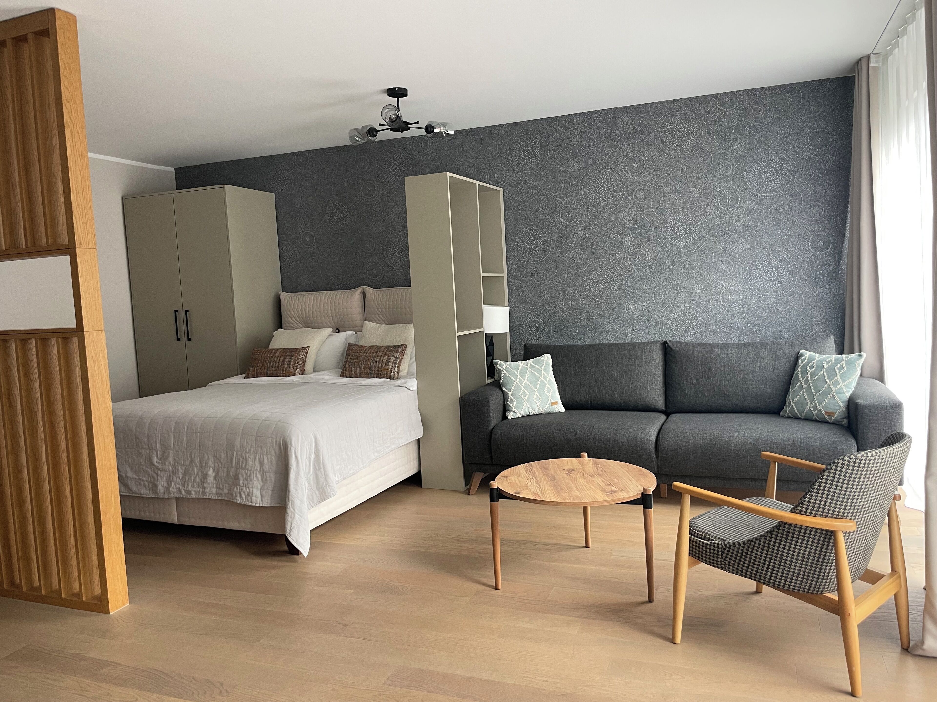 A modern bedroom with a bed, wardrobe, sofa, and a small round table.