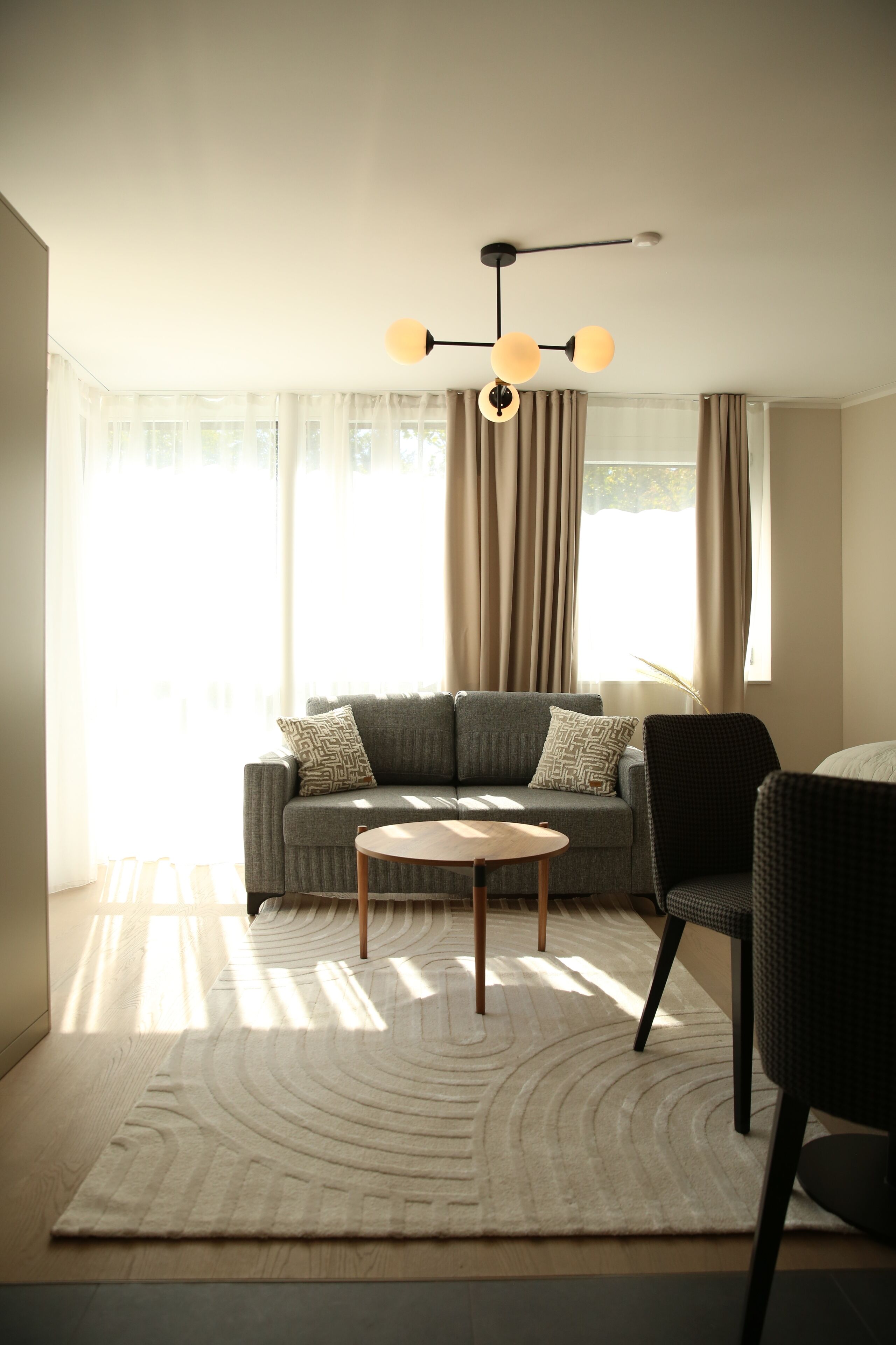 A modern living room with a grey sofa, a round coffee table, and a black armchair.