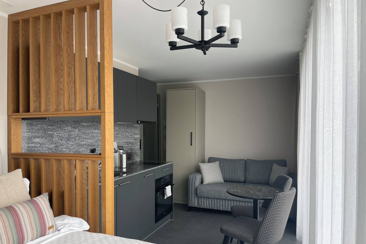 Une chambre d’hôtel moderne équipée d’une kitchenette, d’un canapé, d’une table à manger et d’un lit.