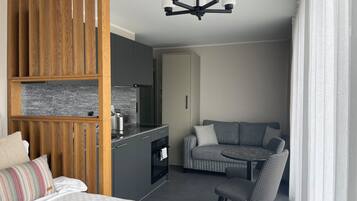 Een moderne hotelkamer met een kitchenette, een bank, een eettafel en een bed.