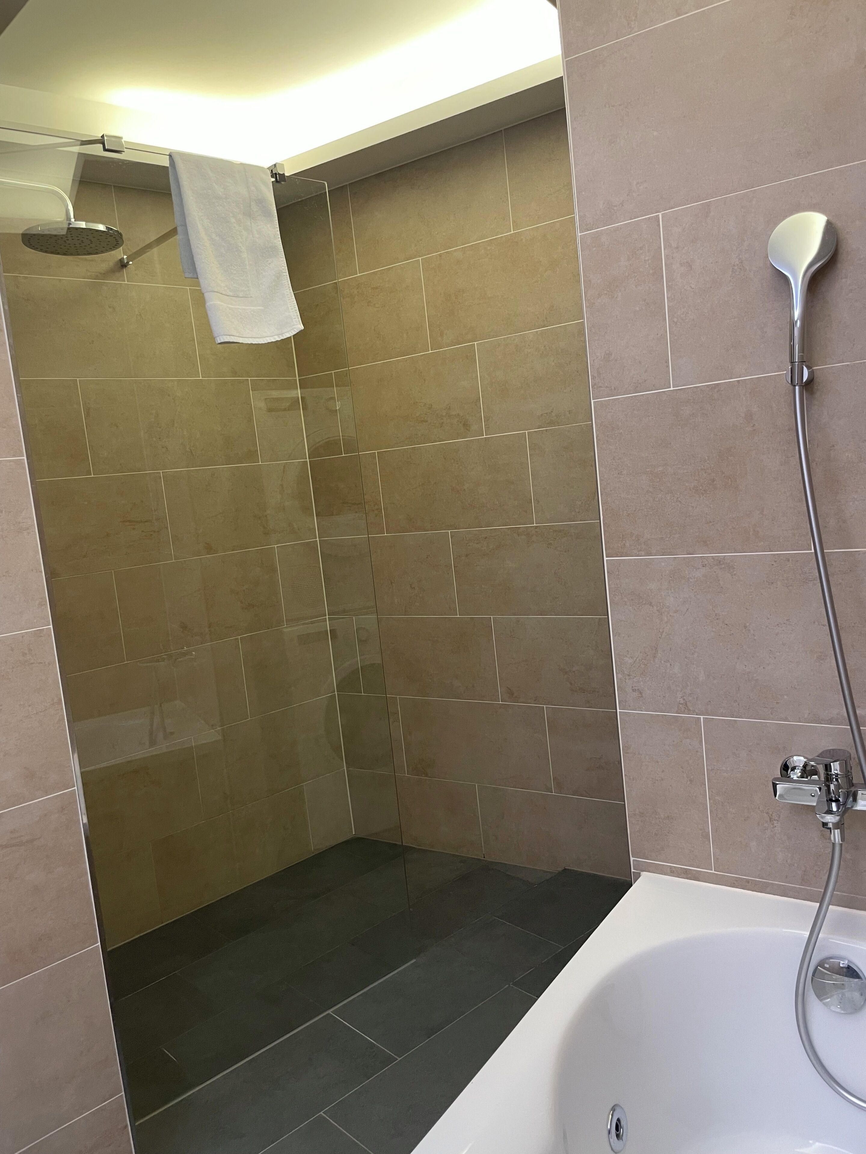 Ein Badezimmer mit Dusche, Badewanne und gefliesten Wänden.