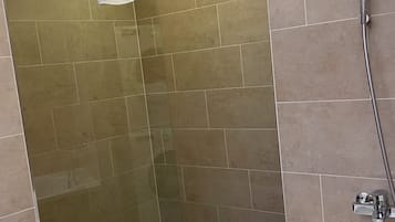 Ein Badezimmer mit Dusche, Badewanne und gefliesten Wänden.
