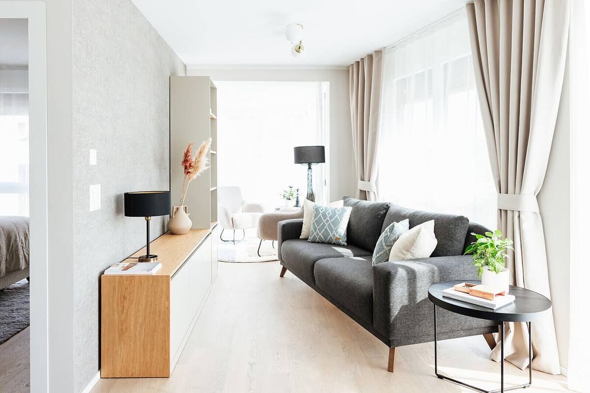 Un salon moderne avec un canapé gris, une petite table ronde et une lampe.