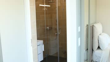 Un baño moderno con cabina de ducha de vidrio, un lavabo blanco y un espejo.