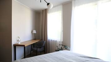 Ein Hotelzimmer mit Bett, Schreibtisch, Stuhl, Lampe und einer Pflanze.