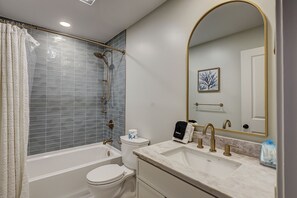 Une salle de bain avec une baignoire, des toilettes, un lavabo et un grand miroir.