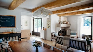 A cozy living room with a wooden dining table, comfortable seating, a fireplace, and a bookshelf. - Mas des Ecoliers (Chateaurenard)