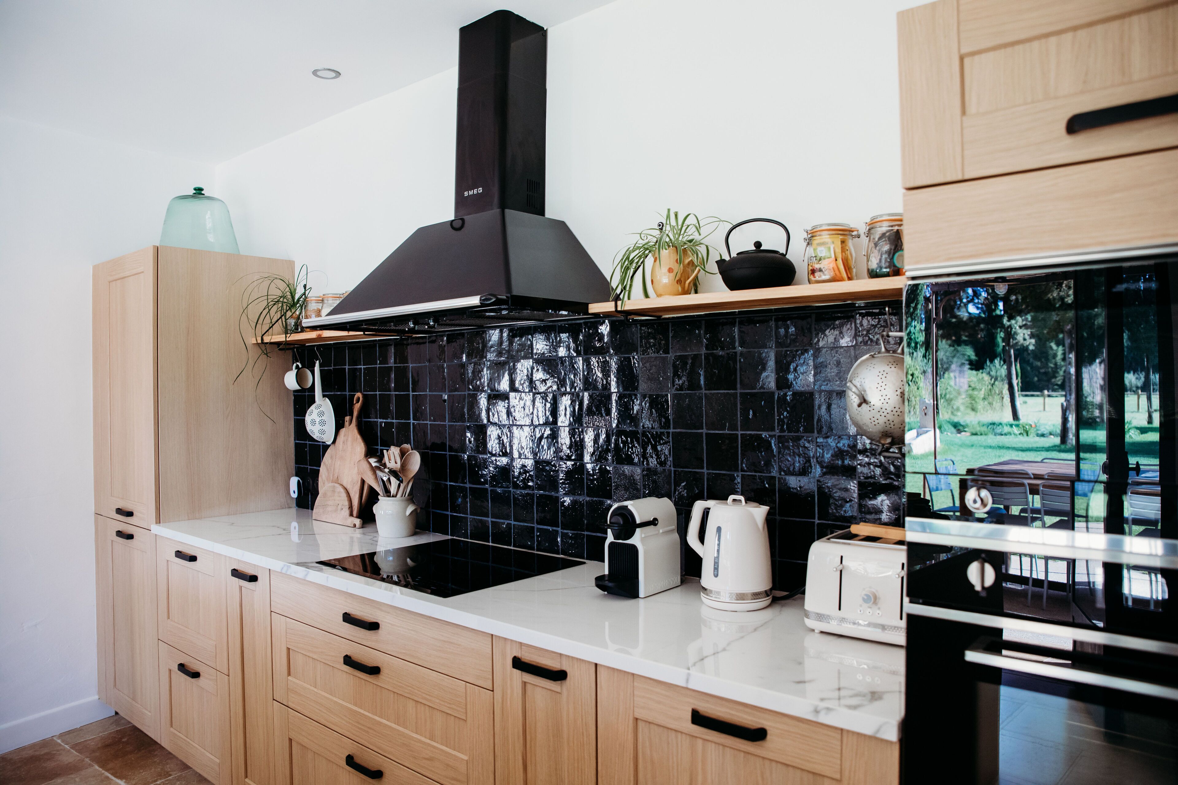 Uma cozinha moderna com armários de madeira, fogão preto e painel de azulejos.