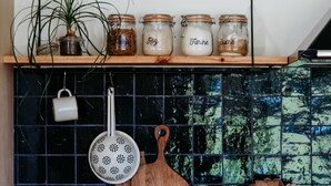 A kitchen with a wooden countertop, a hanging colander, a cutting board, and jars on a shelf. - Mas des Ecoliers (Chateaurenard)