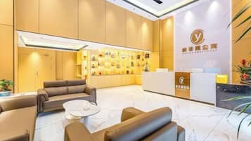 A hotel lobby with a reception desk, seating area, and a wall with framed pictures.