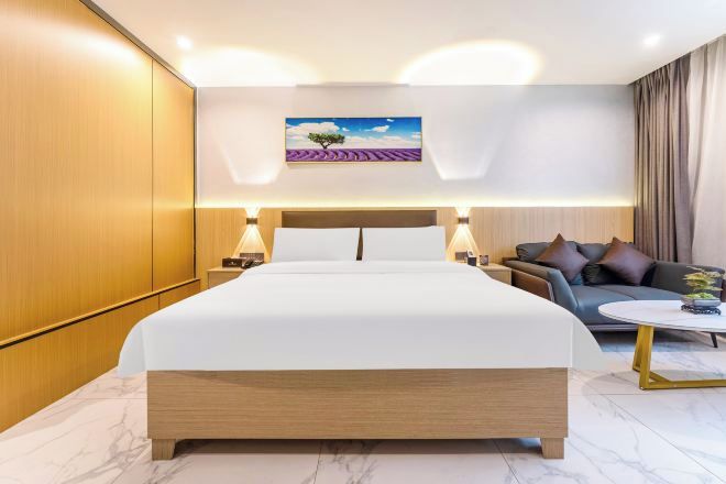 Ein Hotelzimmer mit einem großen Bett, einem Sofa, einem Couchtisch und einem Gemälde an der Wand.