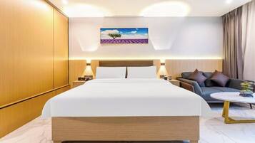Ein Hotelzimmer mit einem großen Bett, einem Sofa, einem Couchtisch und einem Gemälde an der Wand.