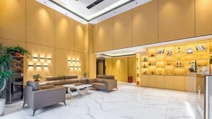 A modern lobby with a marble floor, sofas, a coffee table, and a display of books and decorative items. - Boluo Yanting Business Apartment (Boluo)