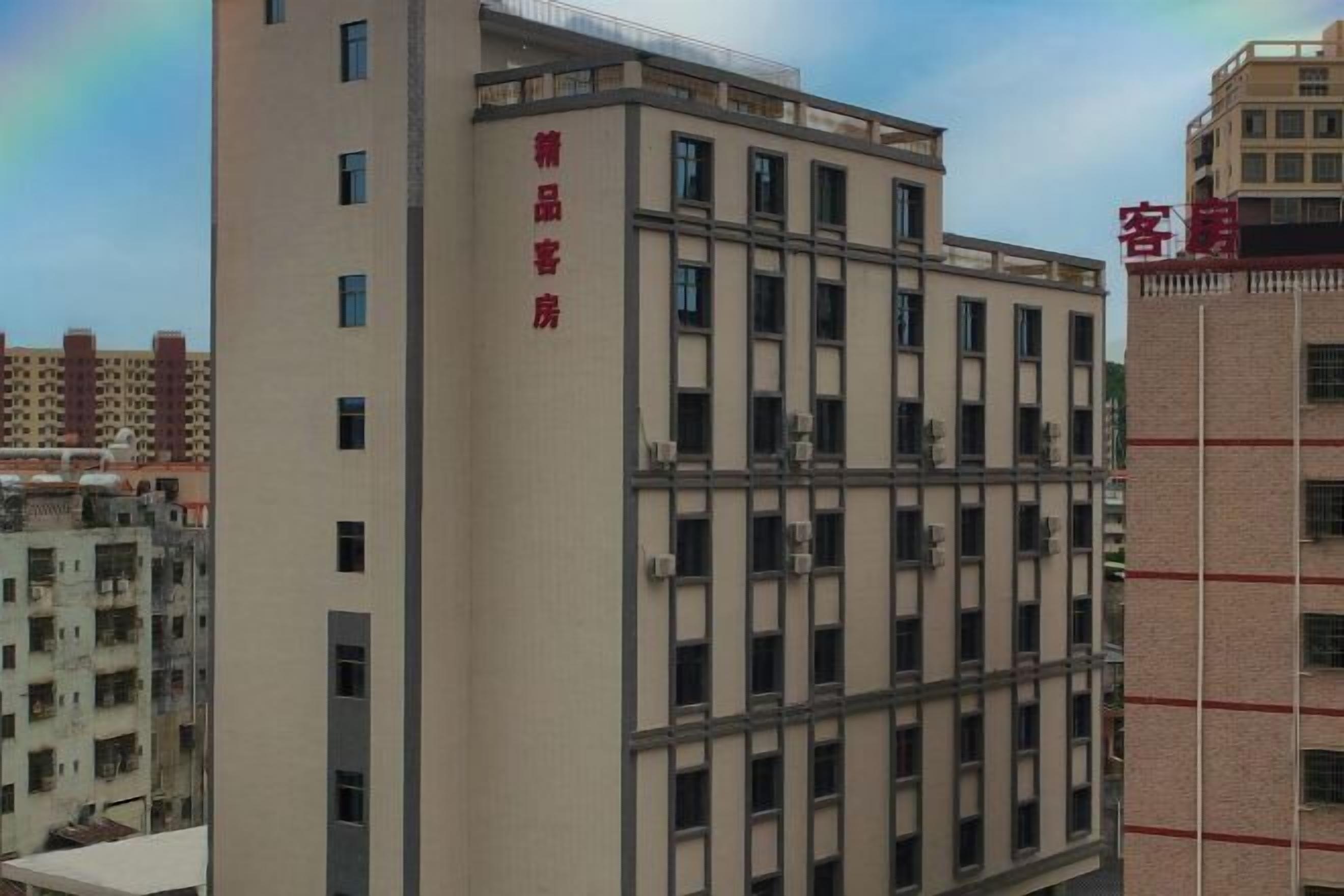 Ein mehrstöckiges Gebäude mit einer beige farbenen Fassade und roter Beschilderung, die es als Gästehaus kennzeichnet.