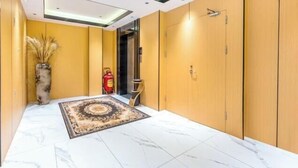 A hallway with wooden doors, a marble floor, and a decorative rug. - Boluo Yanting Business Apartment (Boluo)
