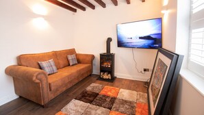 A cozy living room with a brown sofa, a fireplace, a TV mounted on the wall, and a rug on the floor. - Ridley House Apartments (Yarm)