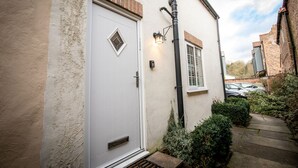 A white door with a small window, a brick section above it, and a light fixture on the wall. - Ridley House Apartments (Yarm)
