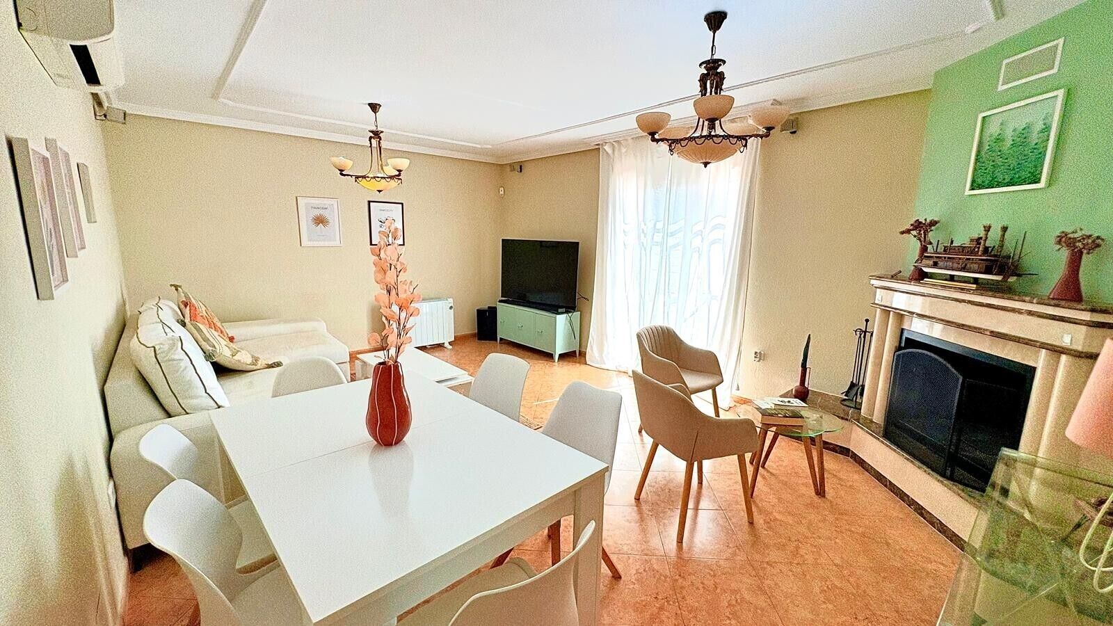 Een woonkamer met een eettafel, stoelen, een open haard en een televisie.