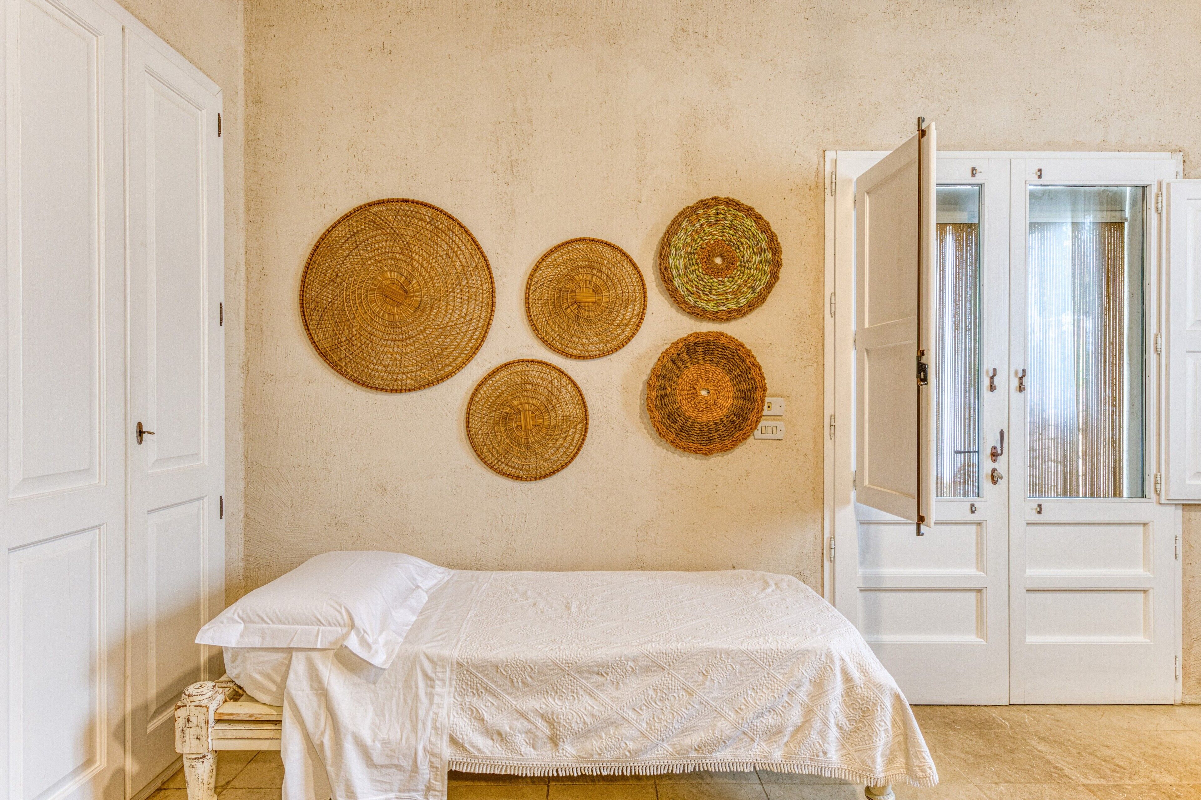 A room with a bed, a wardrobe, and wall-mounted woven baskets.