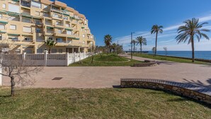 A multi-story hotel with balconies, a paved courtyard, palm trees, and a view of the sea. - Apartment 'Bonito Apartamento Frente Al Mar' with Sea View, Wi-Fi and Air Conditioning (Salobreña)