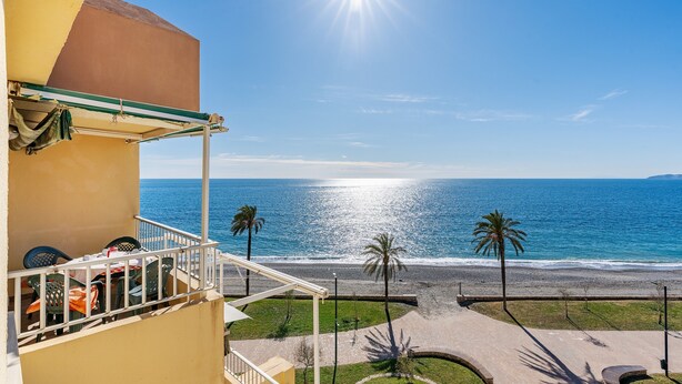 A balcony with outdoor furniture, a view of the sea, and palm trees. - Apartment 'Bonito Apartamento Frente Al Mar' with Sea View, Wi-Fi and Air Conditioning (Salobreña)