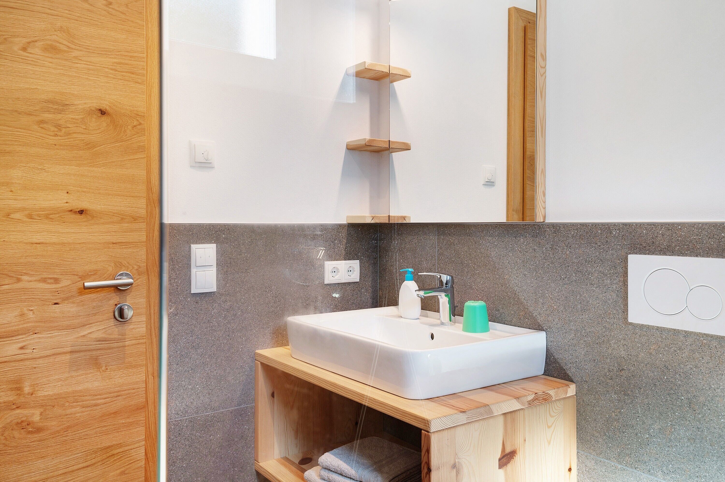 Un bagno con un mobile lavabo in legno, un lavandino bianco, uno specchio e un portasciugamani.