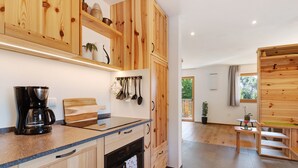 Een moderne keuken met houten kastjes, een koffiezetapparaat en hangend keukengerei.