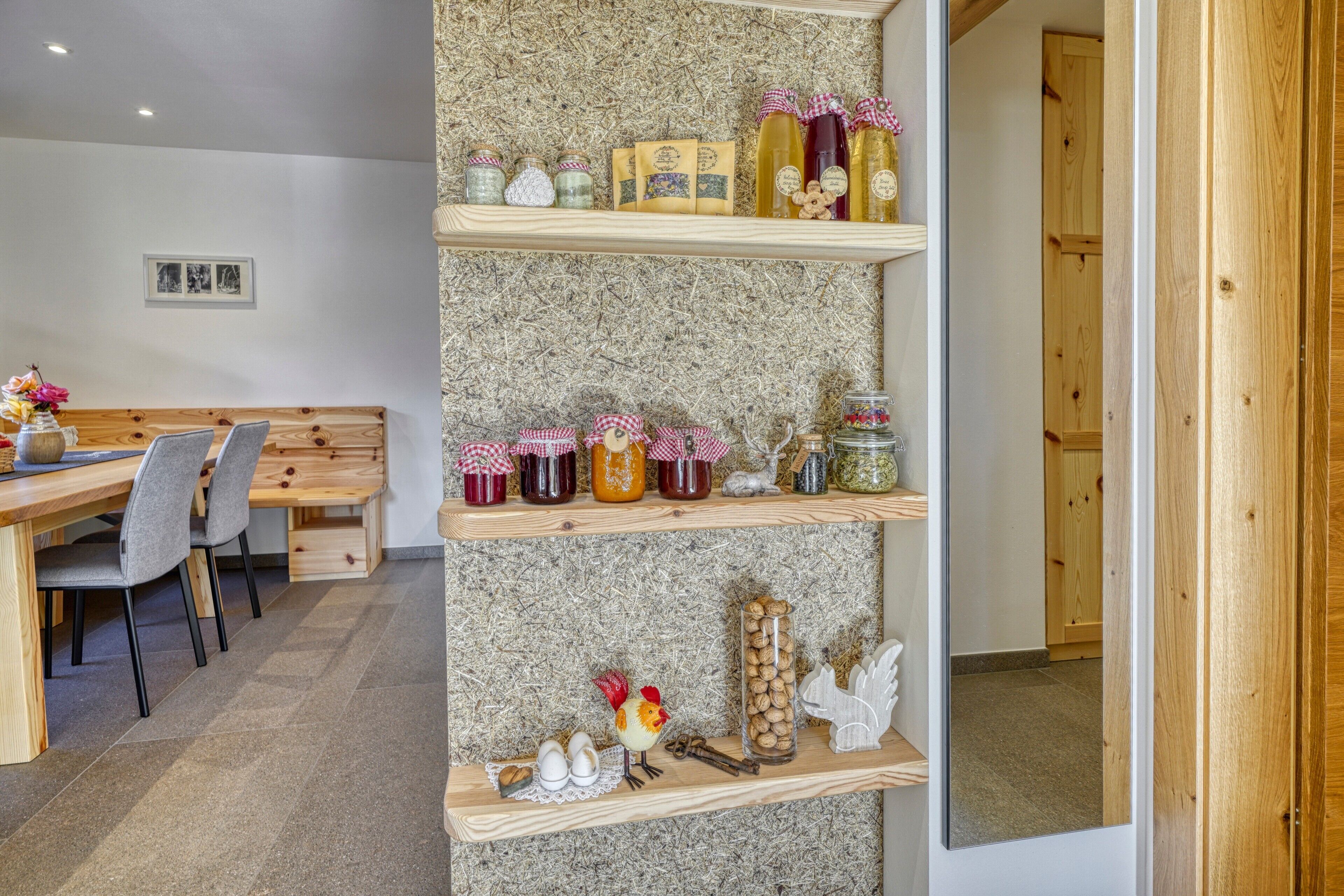 A room with a wooden bench, a dining table, and shelves with jars and decorative items.