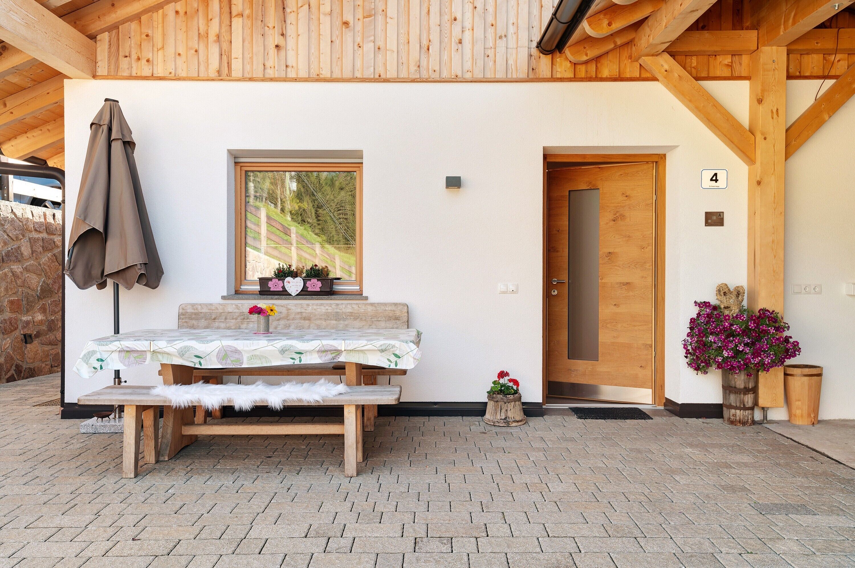A wooden bench and table set outside a building with a wooden door marked with the number 4.