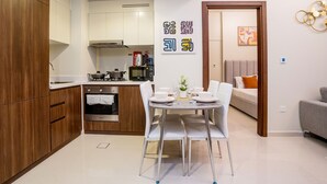 Eine moderne Küche mit weißen Schränken, einem Esstisch mit Stühlen und einem Sofa im angrenzenden Wohnbereich.