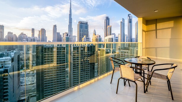 Ein Balkon mit Glasgeländer und Blick auf eine Skyline mit Hochhäusern.