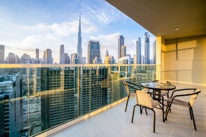 A balcony with a glass railing overlooking a cityscape with high-rise buildings. - Tanin - Fabulous Apt With Burj Khalifa View From Balcony (Dubai)